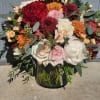 A lush, garden-style arrangement in rich reds, blush, and cream, accented with