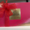 Bright pink Godiva assorted chocolates gift box with gold label and large red ribbon bow