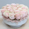 Low round arrangement of pale pink roses tightly packed in a white bowl