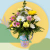 Mixed bouquet in a decorated travel mug with pink, yellow, and white flowers