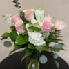 Arrangement of pink roses, white lilies, and white hydrangeas in a clear glass vase