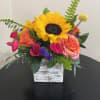 Bright sunflower and mixed roses in a whitewashed wooden cube vase