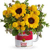 Yellow sunflowers and button mums arranged in a red and white Campbell's soup mug