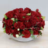 Low round arrangement of red roses in a white ceramic bowl