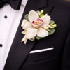 A refined and elegant boutonniere featuring a fresh orchid bloom, accented with