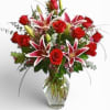 Red roses and pink lilies arranged in a clear glass vase
