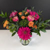 Bright arrangement of hot pink gerbera daisies, pink tulips, and orange roses in a clear glass vase