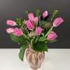 Pink tulip arrangement with small filler flowers in a pink glass vase