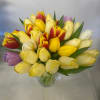 A bunch of bright color tulips in a clear glass vase will