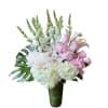 Tall arrangement of white hydrangeas, orchids, snapdragons and pink roses in a glass vase