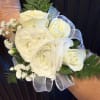 White rose and ranunculus wrist corsage with baby's breath and sheer ribbon.