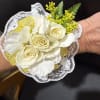 A loose, garden-style corsage with white and yellow florals, airy greenery, and