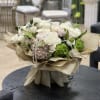Bouquet of white roses and green hydrangeas with pearl strands in beige wrap