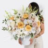 Large bouquet of white, blush, and yellow flowers in a white vase