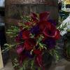 A moody, high-contrast bouquet with velvety red roses and striking purple calla