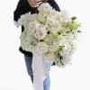 Large hand-tied bouquet of white roses, lilies, hydrangeas, and orchids with long white ribbon tails