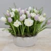 Low arrangement of white and pale lavender tulips in a textured white ceramic bowl