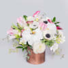 White and pink mixed flower arrangement with orchids and anemones in a copper cylinder vase