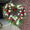 A heart-shaped standing wreath in rich reds and crisp whites designed for