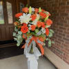 Bright orange roses and gerbera daisies meet large white lilies and cheerful