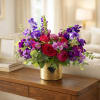 Bouquet of red roses and purple flowers in a gold vase