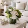 White and green floral arrangement in a glass vase on a coffee table