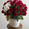 Red roses and white orchids arranged in a white ceramic vase