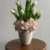 White tulips arranged with pale pink hydrangeas in a textured vase
