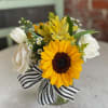 Sunflower bouquet with white tulips and a black-and-white striped ribbon in a glass vase