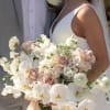 Bride holding a white and blush wedding bouquet with orchids and roses