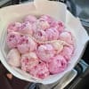 Pink peony bouquet wrapped in white paper with a pearl strand