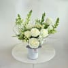White rose arrangement in a white vase with green accents