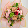 Bouquet of pink and red flowers wrapped in pale pink paper with gold trim
