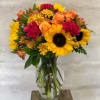 Mixed bouquet with sunflowers, roses, and mums in a clear glass vase