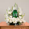 White lilies and roses arranged around a green urn centerpiece