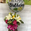 Birthday balloon above a mixed bouquet in a glass vase