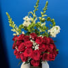 Arrangement of red roses with baby’s breath and tall white flowers in a black vase