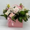 A soft blush rose anchors this floral arrangement, framed by white lilies