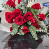 Hand-tied bouquet of red roses with eucalyptus accents wrapped in cream textured paper