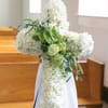White floral cross arrangement with green accents on a stand