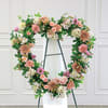 Heart-shaped floral wreath on a stand with pink and white flowers