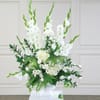 White floral arrangement in a white vase with tall green spikes