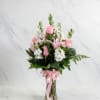 Pink roses and white flowers arranged in a glass vase with a pink ribbon