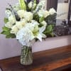 A serene cascade of white roses and a prominent white lily creates