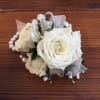 Wrist corsage of white roses and small white blooms on a pearl bracelet