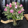 Pink roses arranged in a clear glass vase with small white filler flowers