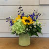 Bright sunflowers, green hydrangea and blue belladonna arranged in a citron inverted