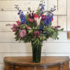 A tall and showy arrangement of bright blue delphinium, hot pink roses