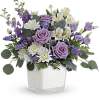 Lavender roses and white flowers in a clear square vase