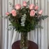 Pink roses arranged in a clear glass vase with eucalyptus foliage